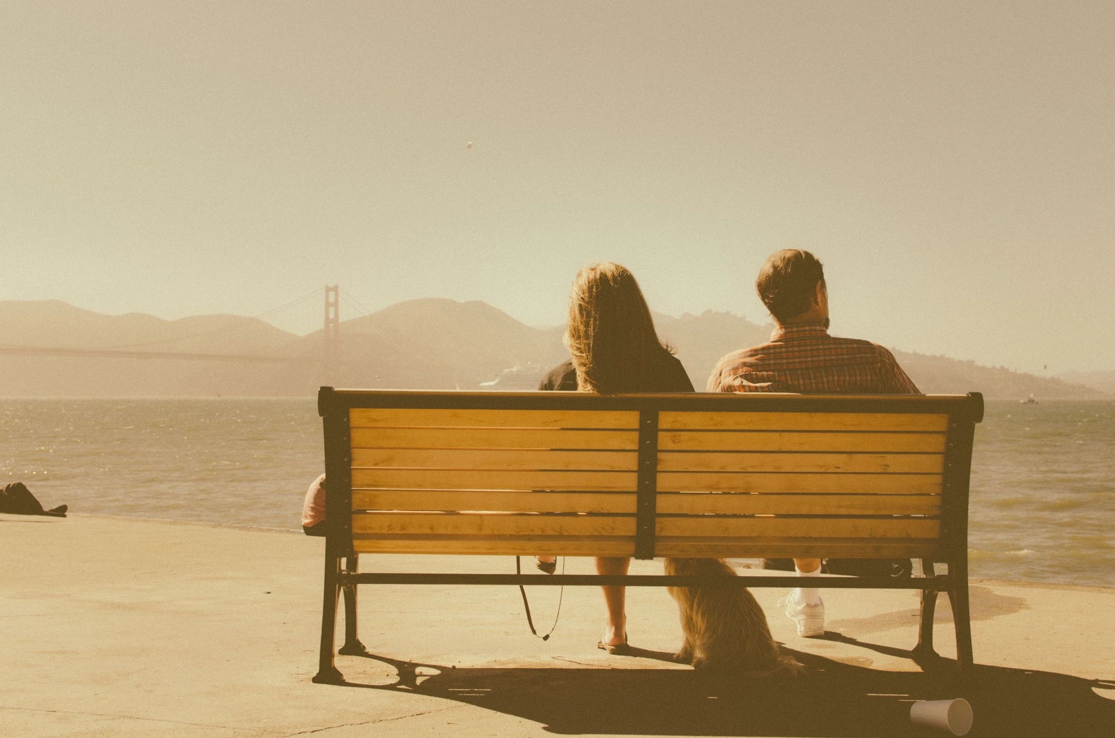 A couple sitting on a bench with their dog